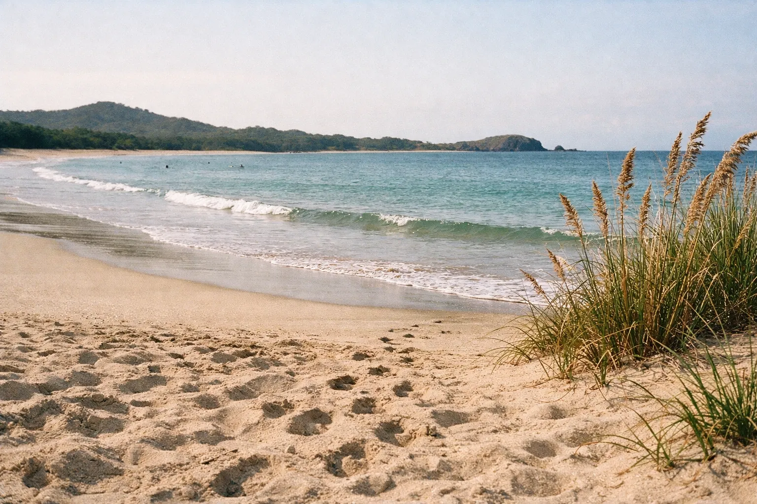 Wide landscape of Tamarindo Beach with textured wet and dry sand, no people in foreground