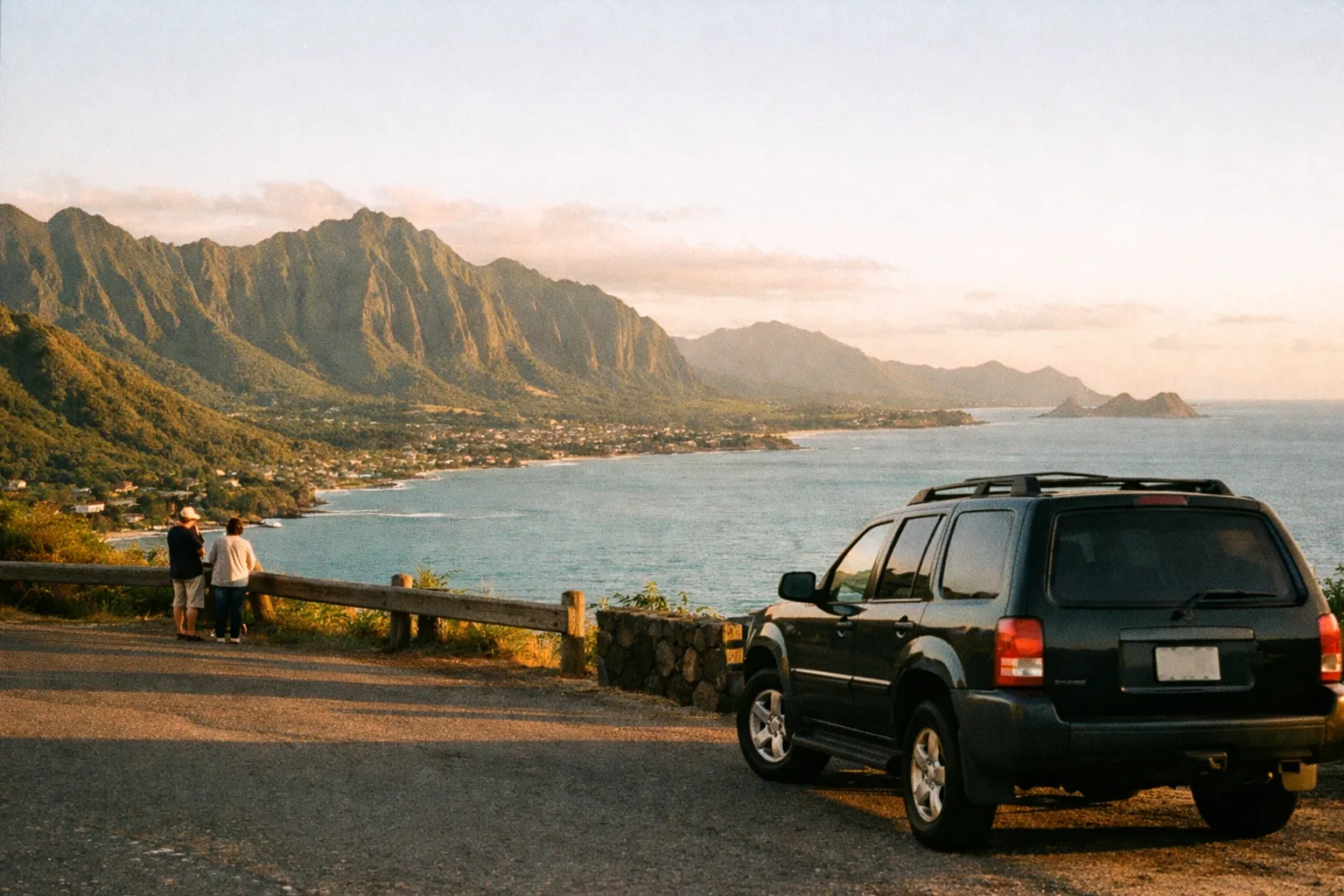 Lookout over Oahus Windward Coast with emerald Koolau mountains and a parked SUV, hints of Lanikai Beach in the distance