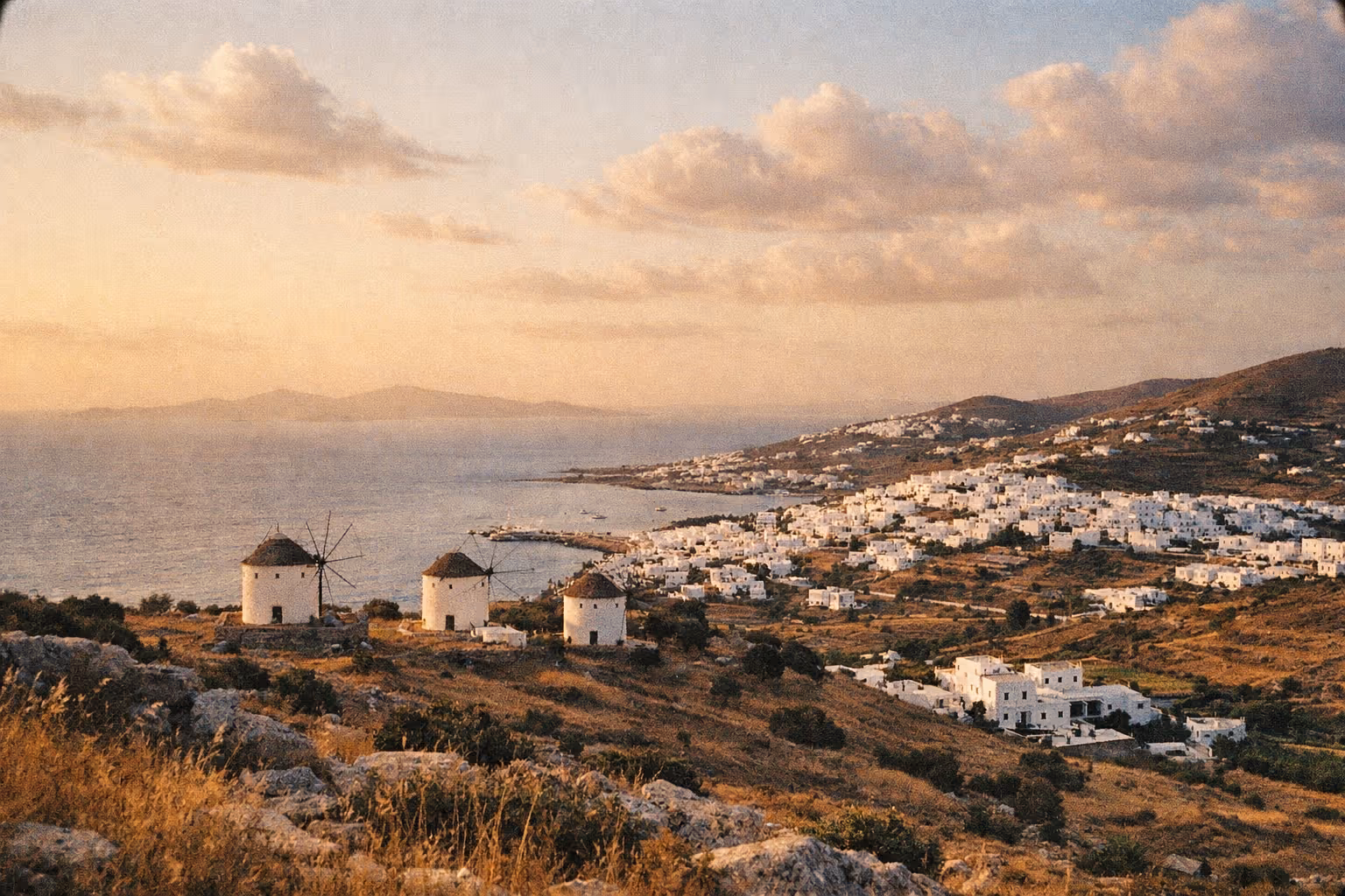 Golden-hour aerial view of Paros: white marble villages, windmills, and the blue Aegean Sea