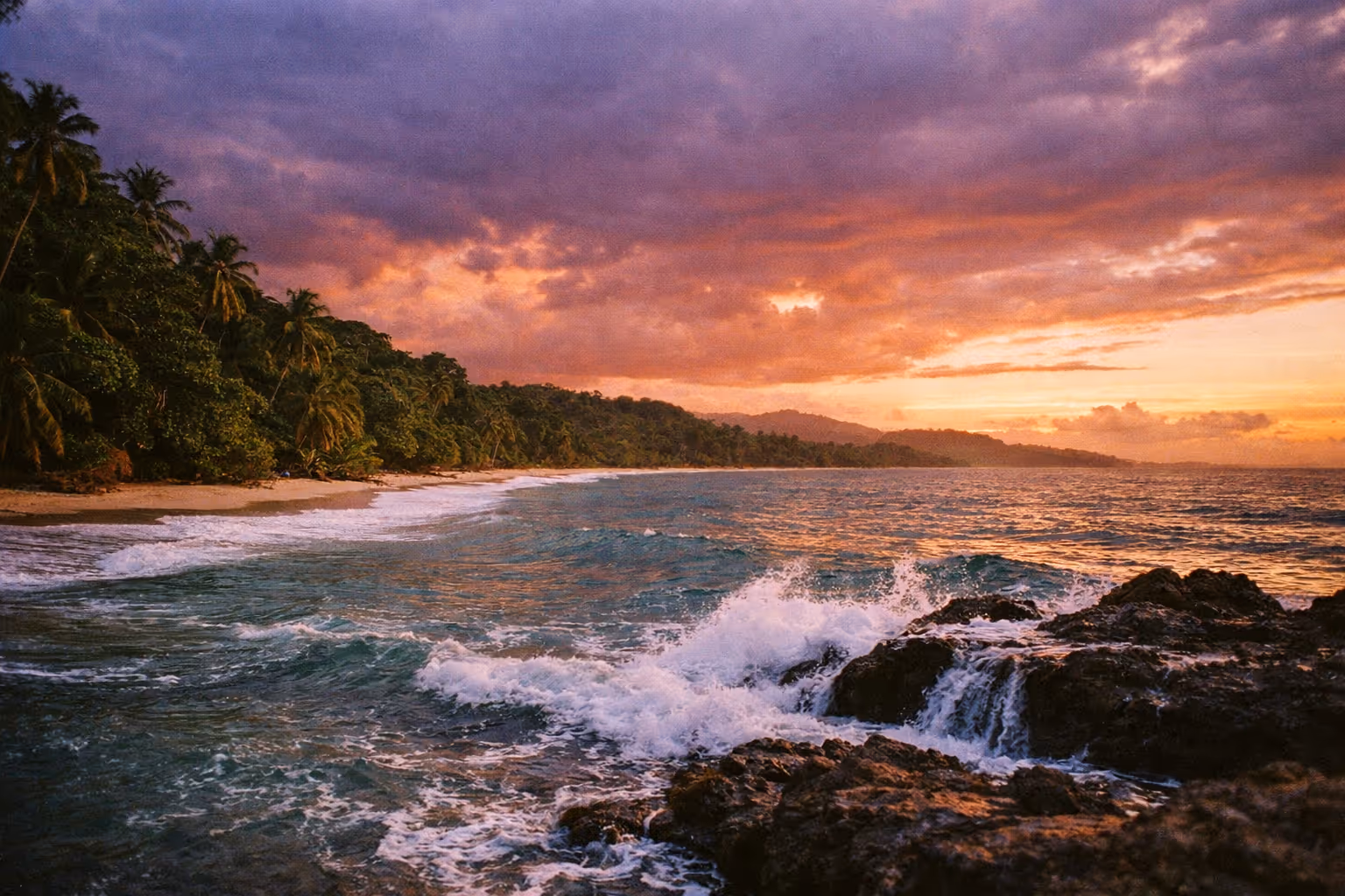 Panoramic view of Puerto Viejo's tropical coastline at sunset, with jungle meeting the Caribbean Sea and a dramatic sky.