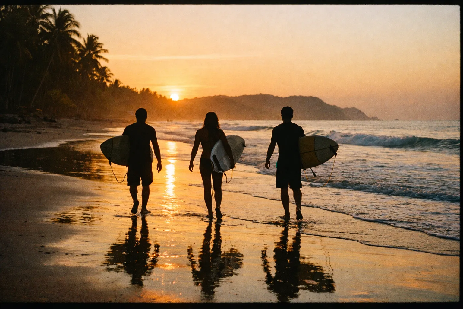 Surfers walking with boards along Playa Carmen at sunset