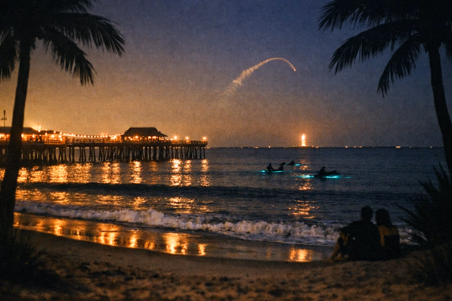 Nighttime Cocoa Beach editorial scene: pier lights, bioluminescent water, and a distant rocket launch plume over the horizon.