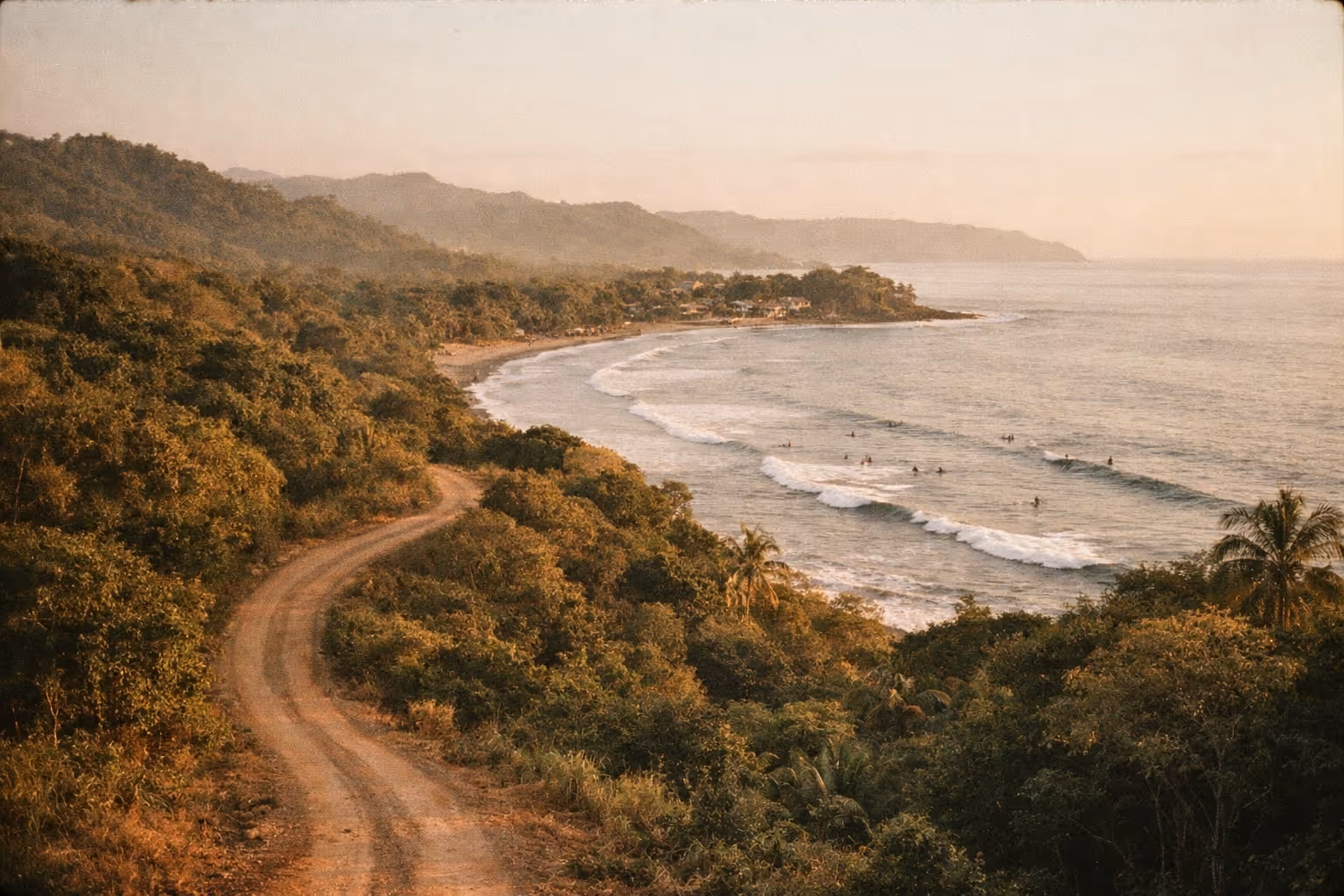 Golden-hour panorama of Costa Rica’s lush coastline and rainforest, a winding road leading toward a small village